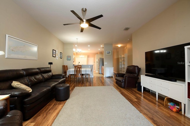 living room featuring ceiling fan with notable chandelier and hardwood / wood-style flooring