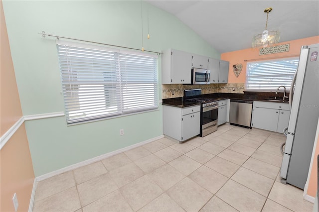 kitchen with lofted ceiling, backsplash, sink, stainless steel appliances, and white cabinets