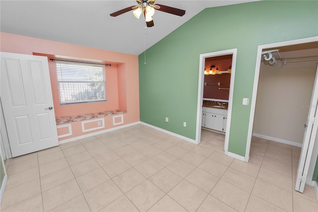 unfurnished bedroom with light tile patterned floors, ensuite bathroom, ceiling fan, a closet, and lofted ceiling