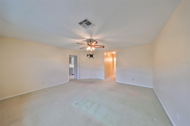 unfurnished room featuring ceiling fan, light carpet, and a textured ceiling