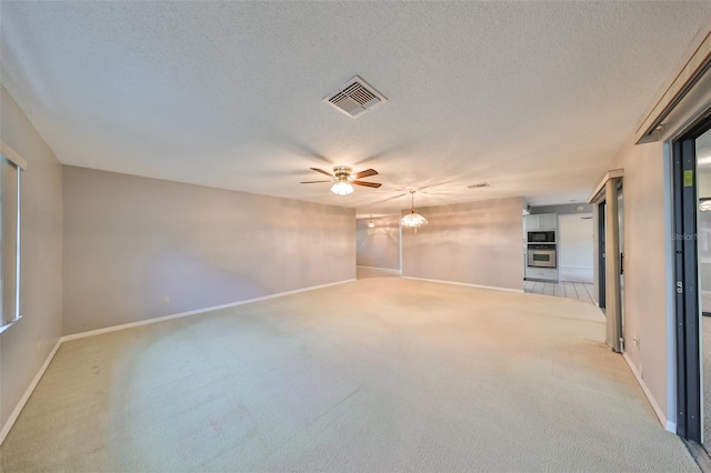 carpeted spare room featuring ceiling fan with notable chandelier and a textured ceiling