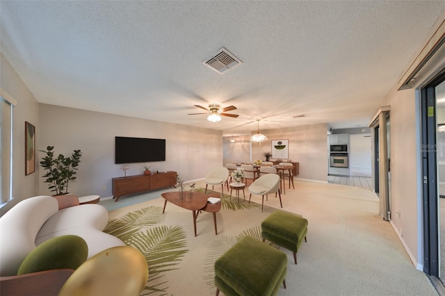 living room featuring ceiling fan with notable chandelier, a textured ceiling, and light carpet