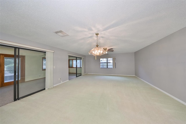 unfurnished room featuring light colored carpet, ceiling fan with notable chandelier, and a textured ceiling