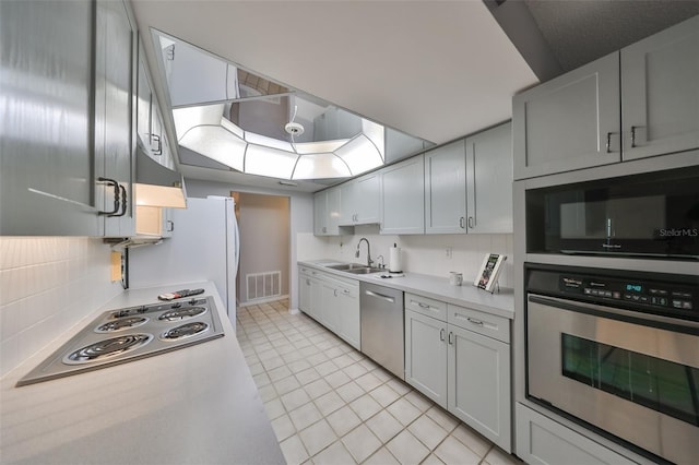 kitchen featuring light tile patterned floors, stainless steel appliances, tasteful backsplash, range hood, and sink