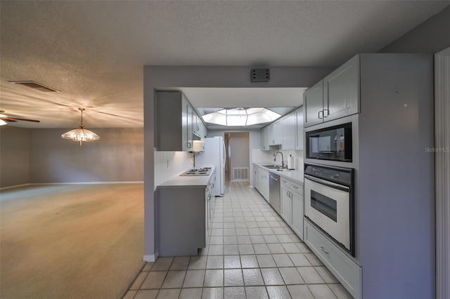 kitchen featuring a textured ceiling, a skylight, stainless steel appliances, sink, and light tile patterned floors