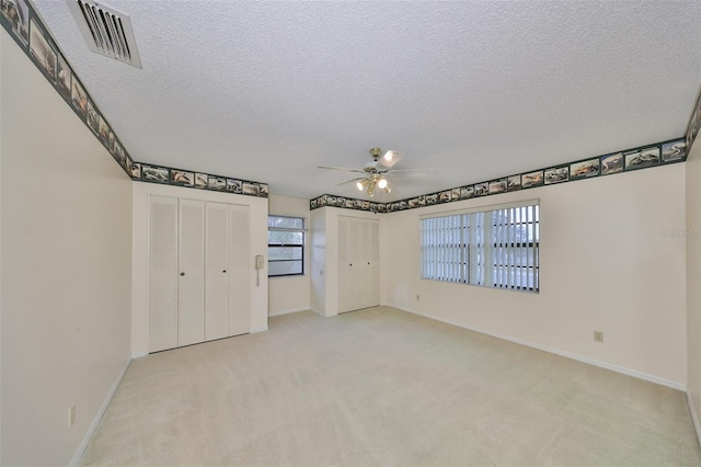 unfurnished bedroom with light carpet, ceiling fan, and a textured ceiling