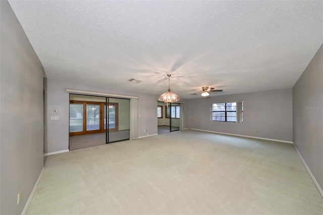 spare room featuring a textured ceiling, ceiling fan with notable chandelier, and light colored carpet