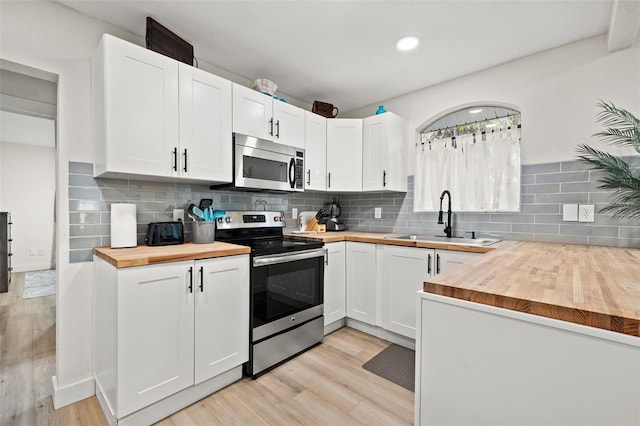 kitchen with appliances with stainless steel finishes, white cabinets, wooden counters, and sink