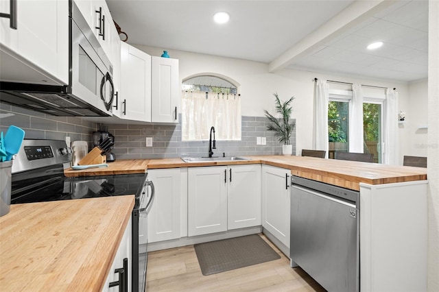 kitchen featuring backsplash, sink, appliances with stainless steel finishes, white cabinets, and butcher block counters