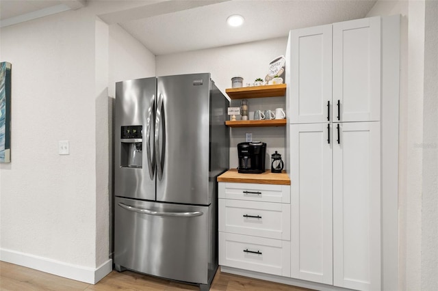 kitchen featuring stainless steel refrigerator with ice dispenser, white cabinetry, butcher block counters, and light wood-type flooring