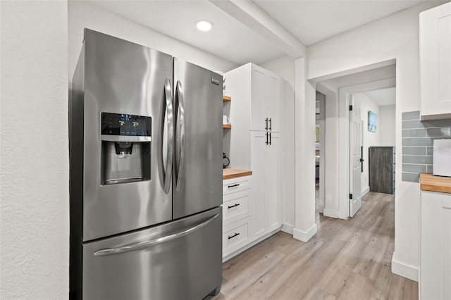 kitchen featuring stainless steel refrigerator with ice dispenser, white cabinetry, light hardwood / wood-style flooring, and wooden counters