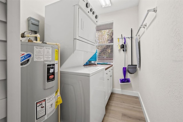 washroom with cabinets, stacked washer / drying machine, light hardwood / wood-style floors, and electric water heater