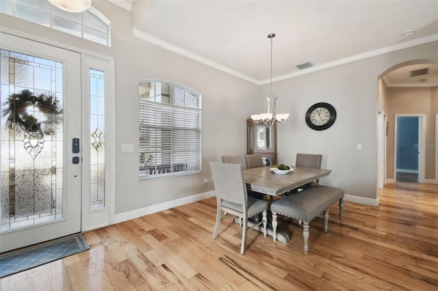 dining space with an inviting chandelier, light wood-type flooring, and ornamental molding