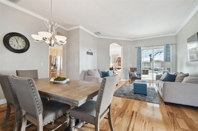 dining area with an inviting chandelier, ornamental molding, and light hardwood / wood-style flooring