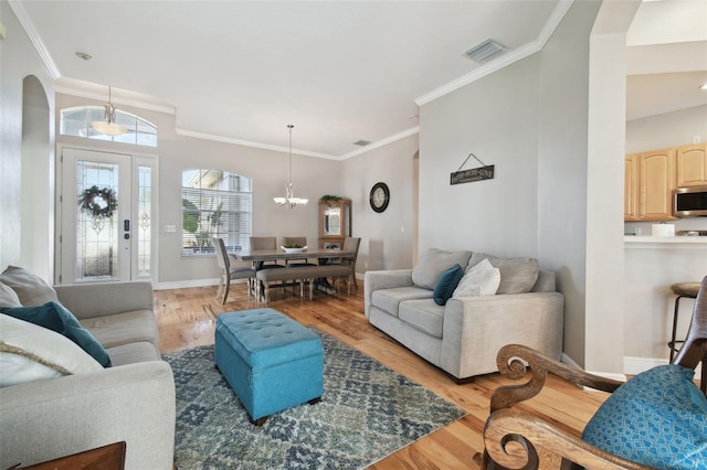 living room with an inviting chandelier, crown molding, and light hardwood / wood-style flooring