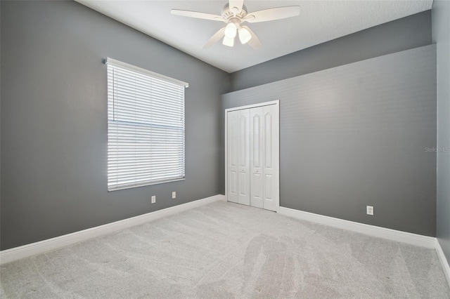 unfurnished bedroom with light carpet, a closet, and ceiling fan