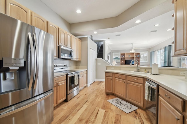 kitchen featuring light wood-type flooring, crown molding, appliances with stainless steel finishes, ceiling fan, and sink