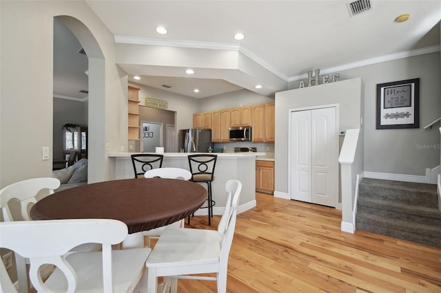 dining area with ornamental molding and light hardwood / wood-style floors