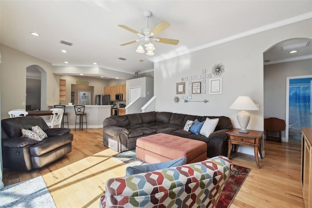 living room with light wood-type flooring, ceiling fan, and crown molding