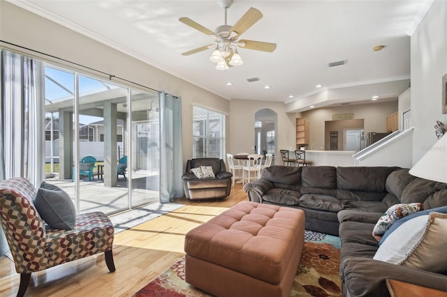 living room with ornamental molding, ceiling fan, and light wood-type flooring