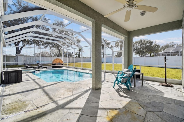 view of swimming pool with ceiling fan, a yard, glass enclosure, and a patio area