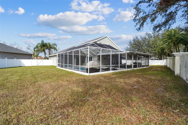 back of property featuring glass enclosure, a yard, and a fenced in pool