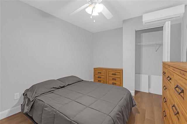 bedroom with ceiling fan, an AC wall unit, a closet, and hardwood / wood-style floors