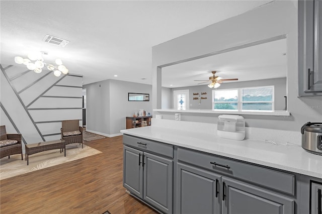 kitchen with ceiling fan, light stone countertops, dark hardwood / wood-style floors, and gray cabinetry