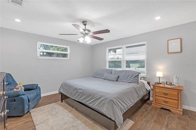 bedroom featuring ceiling fan, multiple windows, and dark hardwood / wood-style flooring