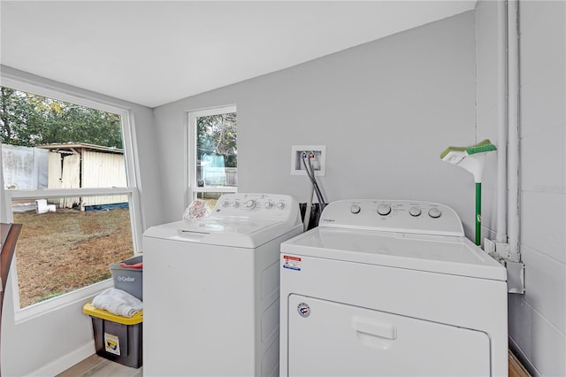 laundry area with light hardwood / wood-style floors, a wealth of natural light, and washer and clothes dryer