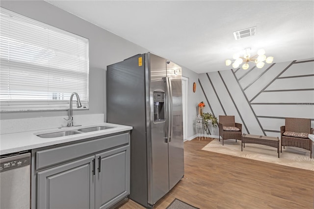 kitchen featuring a notable chandelier, gray cabinets, sink, dark wood-type flooring, and appliances with stainless steel finishes