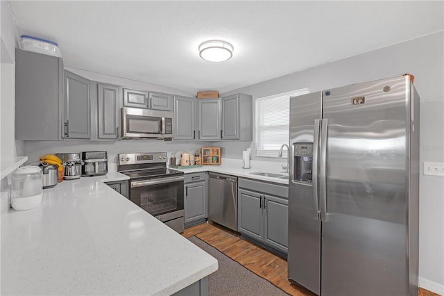 kitchen featuring light wood-type flooring, stainless steel appliances, gray cabinetry, and sink