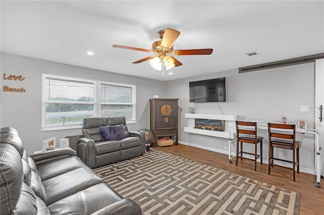 living room featuring ceiling fan and dark hardwood / wood-style floors