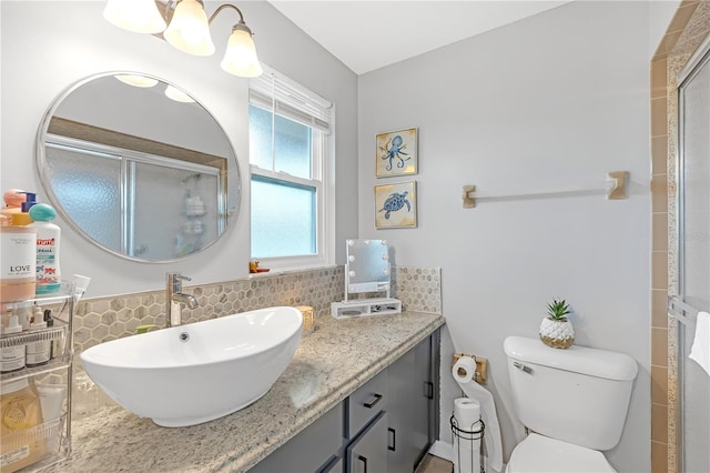 bathroom with toilet, backsplash, a shower with door, and vanity