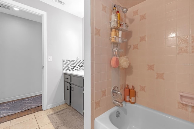 bathroom featuring vanity, decorative backsplash, tiled shower / bath combo, and tile patterned floors