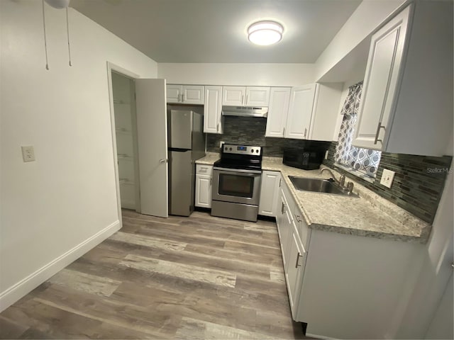 kitchen with sink, appliances with stainless steel finishes, white cabinetry, light hardwood / wood-style floors, and decorative backsplash