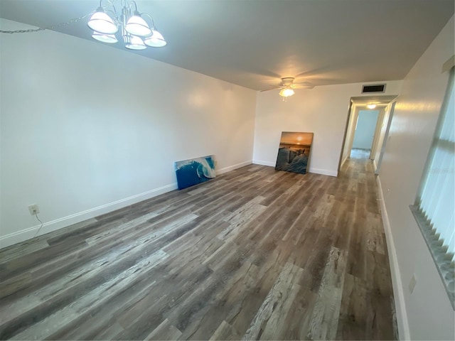 unfurnished living room featuring ceiling fan with notable chandelier and dark hardwood / wood-style flooring