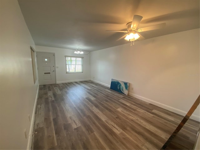 spare room with ceiling fan with notable chandelier and dark hardwood / wood-style flooring