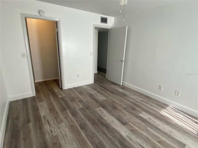 unfurnished bedroom with a closet, a spacious closet, and dark hardwood / wood-style floors