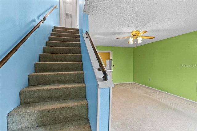 stairs featuring carpet flooring, a textured ceiling, and ceiling fan