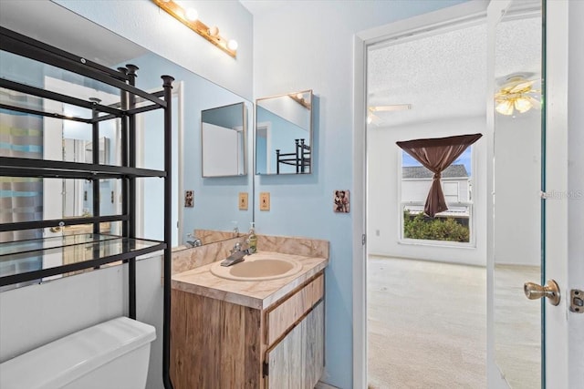 bathroom featuring a textured ceiling, ceiling fan, vanity, and toilet