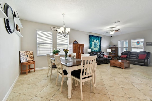 dining room with ceiling fan with notable chandelier, a wealth of natural light, and light tile patterned flooring