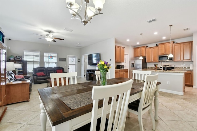 tiled dining room with ceiling fan with notable chandelier and sink