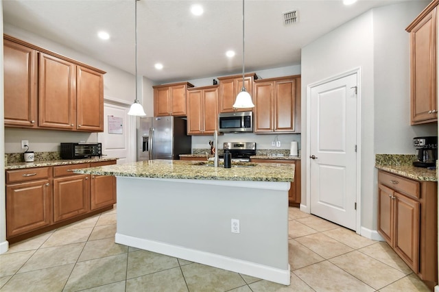 kitchen featuring light tile patterned floors, appliances with stainless steel finishes, hanging light fixtures, and light stone countertops