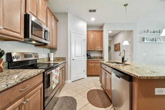 kitchen with appliances with stainless steel finishes, decorative light fixtures, sink, light tile patterned floors, and a center island with sink