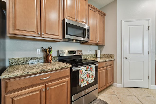 kitchen featuring light stone counters, stainless steel appliances, and light tile patterned flooring