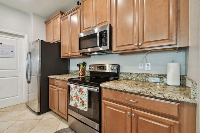 kitchen featuring light stone countertops, appliances with stainless steel finishes, and light tile patterned flooring