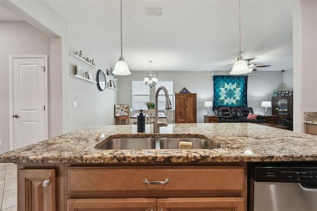 kitchen with ceiling fan with notable chandelier, light stone countertops, an island with sink, sink, and stainless steel dishwasher