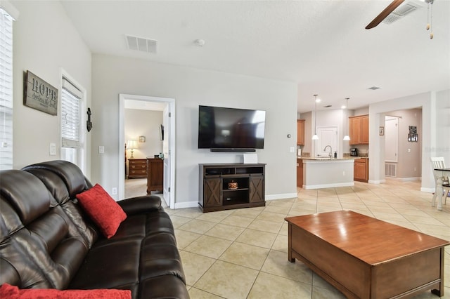 living room featuring ceiling fan, sink, and light tile patterned flooring