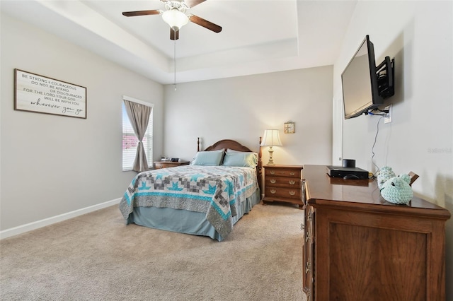 carpeted bedroom with ceiling fan and a raised ceiling